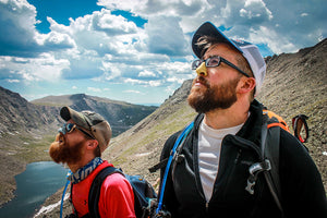 Two men outdoors wearing sunscreen on nose 